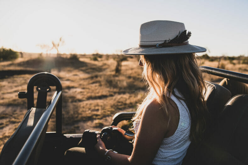 Girl on safari with safari hat and camera, backlit