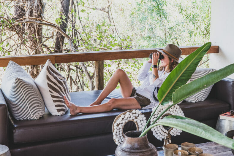 Girl laying on day bed using binoculars at Tree Camp Londolozi